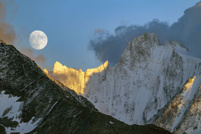Pleine lune au-dessus des Grandes Jorasses enneigées, éclairées par les derniers rayons du soleil